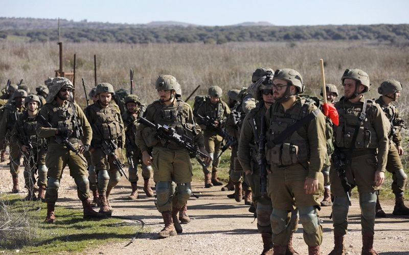 Israeli soldiers walk near Moshav Sha'al in the Israeli-annexed Golan Heights on February 9, 2022. - Israel launched strikes against targets in Syria early today, hitting anti-aircraft batteries in response to a missile fired from Syria, the military said. (Photo by JALAA MAREY / AFP)